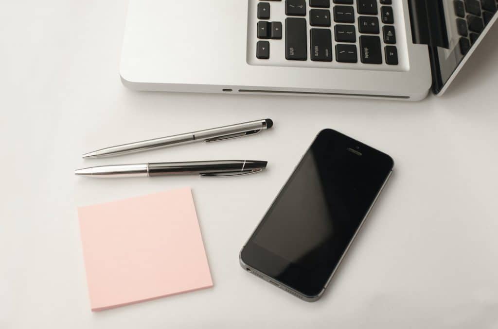 Space Gray Iphone 6 Beside Two Retractable Pens and Macbook