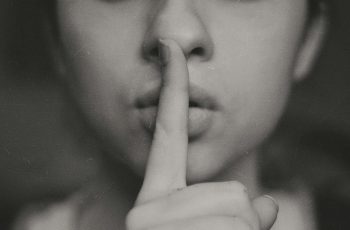 grayscale photo of woman doing silent hand sign