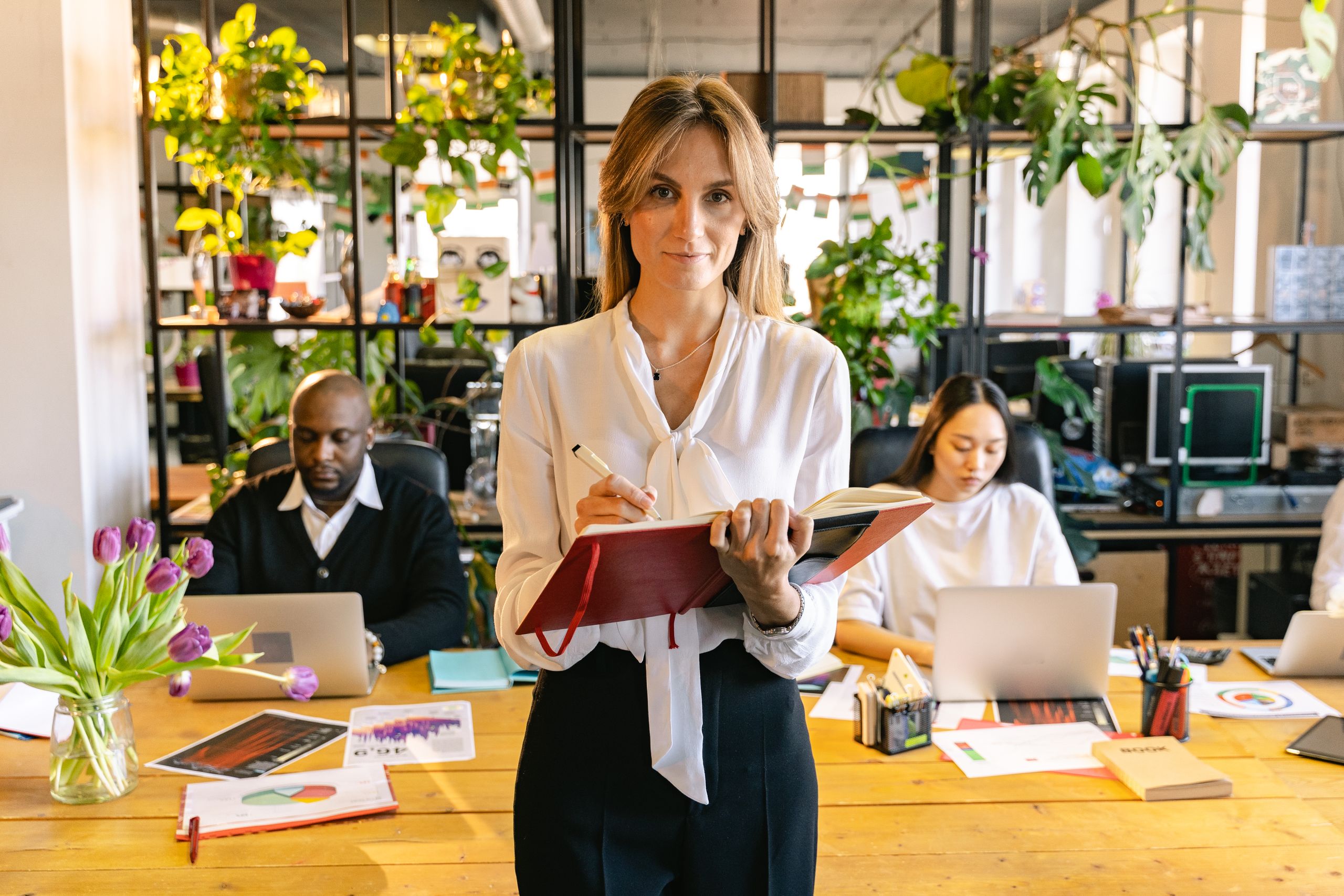 Diverse group of professionals collaborating in a greenery-filled modern office.