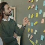 Two colleagues discuss sticky notes on a wall